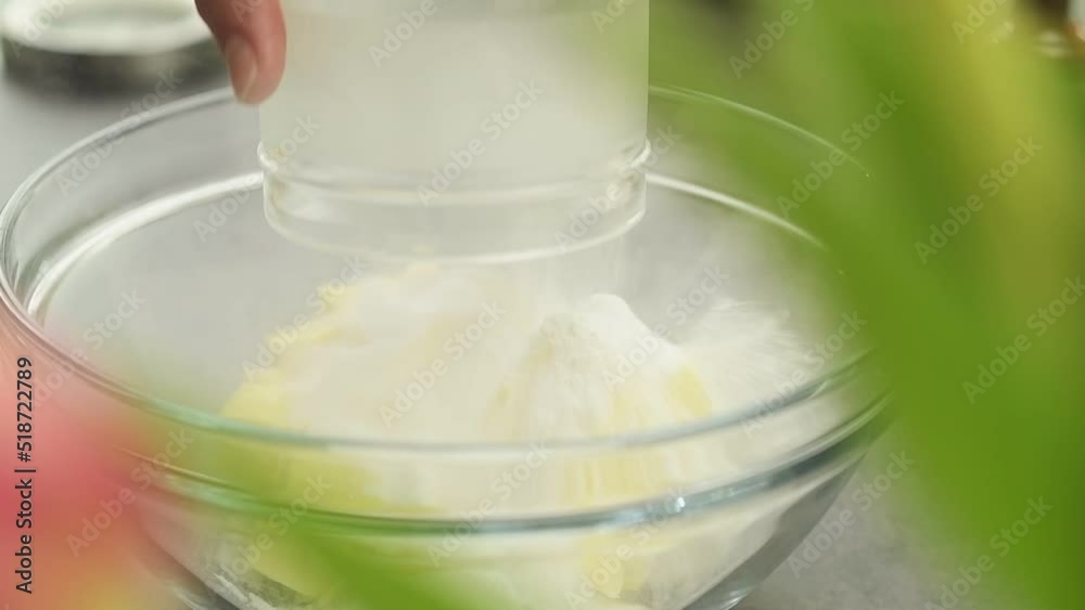 The confectioner adds powdered sugar on butter in a glass bowl.
The confectioner adds powdered sugar on butter in a glass bowl.