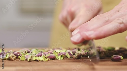 Cutting raw pistachios on a wooden cutting board, slow motion.
