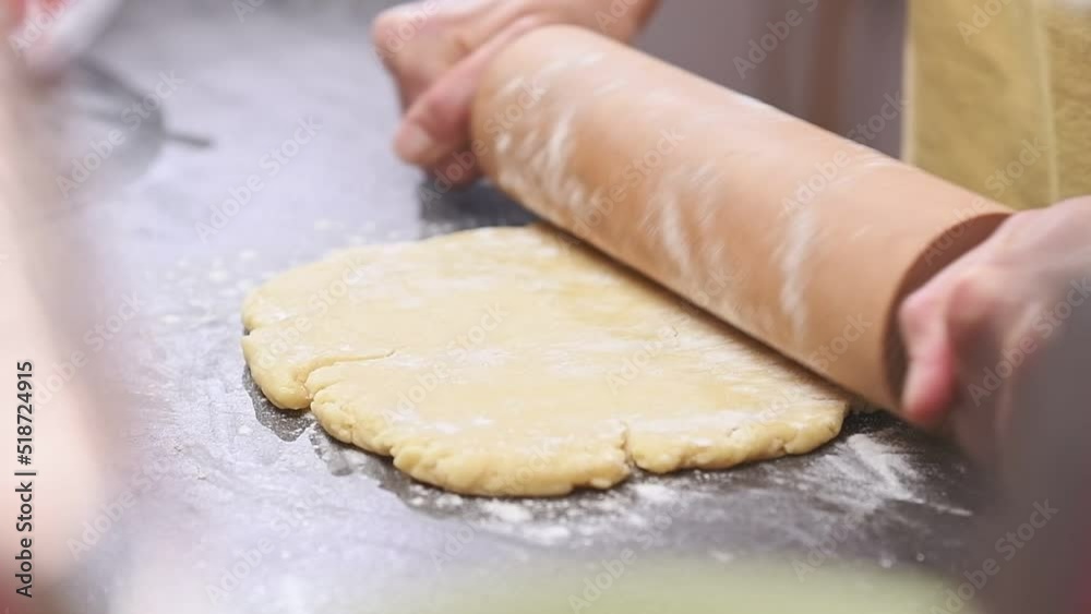 Female hands rolling out dough with a rolling pin.
Female hands rolling out dough with a rolling pin.