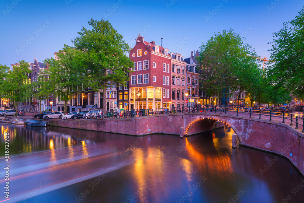 Fototapeta premium Amsterdam, Netherlands. View of houses and bridges during sunset. The famous Dutch canals and bridges. A cityscape in the evening. Travel photography.