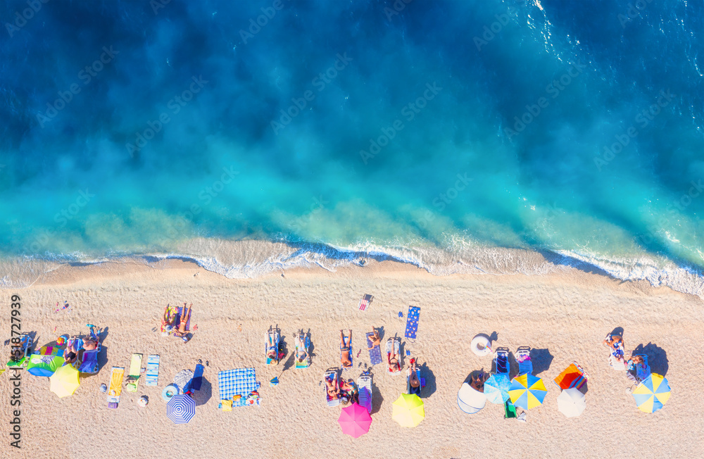Aerial view on the beach, people and umbrellas. Vacation and adventure. Beach and blue water. Top view from drone at beach and azure sea. View on the coast from drone.