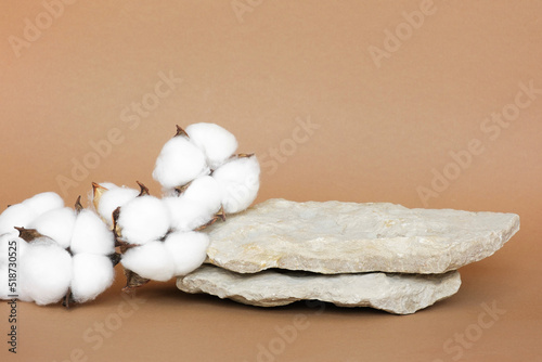 Stone Podium for promotion on beige Background. Natural pedestal. Rock. Beauty product mockup. Scene to show products. Showcase, display case. Front View, soft shadow. Cotton flowers, wooden branch