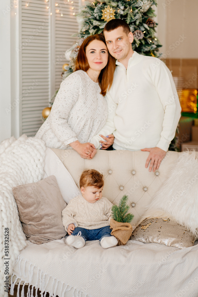 a little son on the couch, mom and dad behind the couch at the christmas tree a little son on the couch, mom and dad behind the couch at the christmas tree