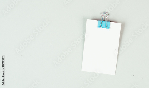 Blank white paper with a paperclip on a gray colored background, copy space for text, reminder or message in the office, communication concept