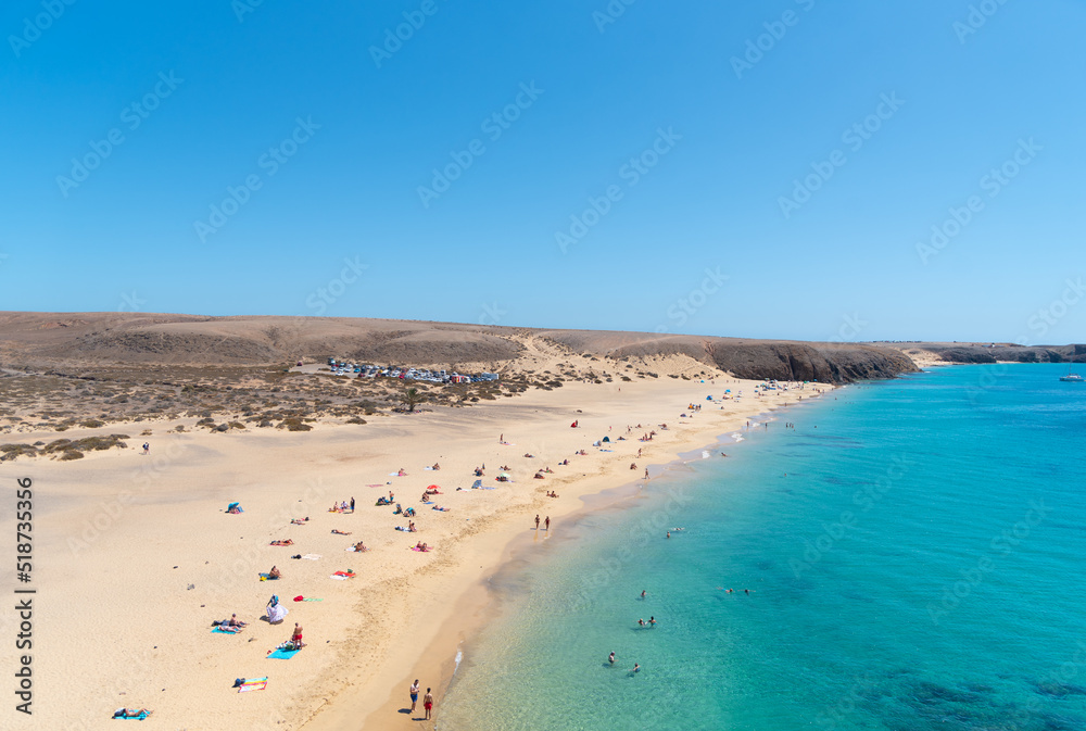 vista de la playa mujeres en Lanzarote, isla canarias. Turistas tomando el sol en la playa en un día de verano con el cielo azul y sol. Islas de España.