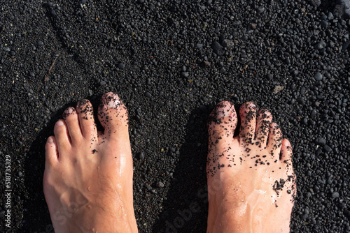 detalle de unos pies caucásicos en una arena negra de una playa de Lanzarote en las Islas canarias. 