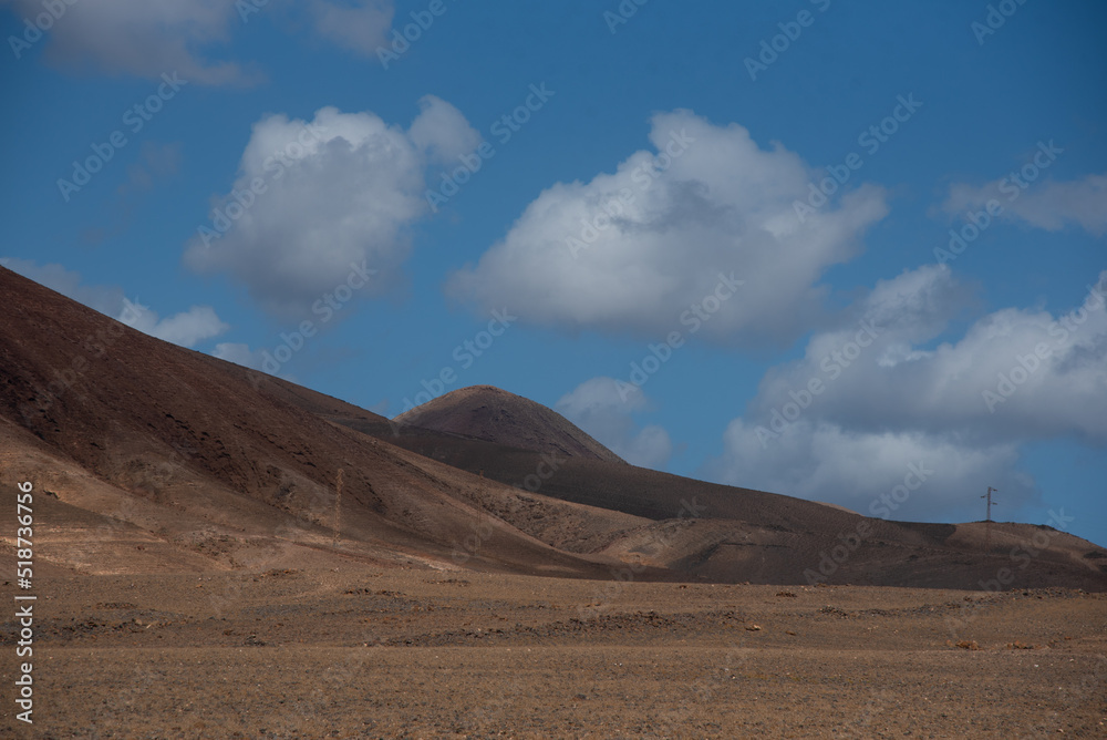 Vista panorámica del Parque Nacional de Timanfaya, impresionante paisaje volcánico y desértico con  montañas en sombra durante un día soleado con el cielo azul y nubes en Lanzarote Islas Canarias.