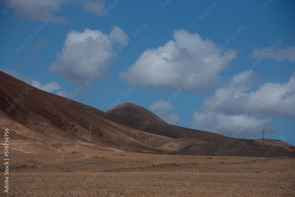 Vista panorámica del Parque Nacional de Timanfaya, impresionante paisaje volcánico y desértico con montañas en sombra durante un día soleado con el cielo azul y nubes en Lanzarote Islas Canarias. Vista panorámica del Parque Nacional de Timanfaya, impresionante paisaje volcánico y desértico con montañas en sombra durante un día soleado con el cielo azul y nubes en Lanzarote Islas Canarias.