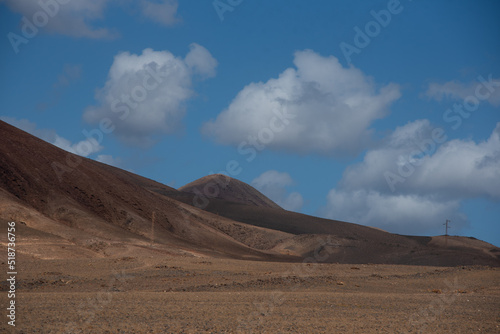 Vista panorámica del Parque Nacional de Timanfaya, impresionante paisaje volcánico y desértico con montañas en sombra durante un día soleado con el cielo azul y nubes en Lanzarote Islas Canarias.