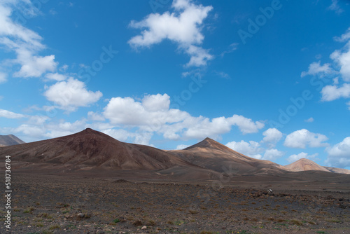 Vista panorámica del Parque Nacional de Timanfaya, un paisaje volcánico y desértico con dos grandes montañas en sombra durante un día soleado con el cielo azul y nubes en Lanzarote Islas Canarias.