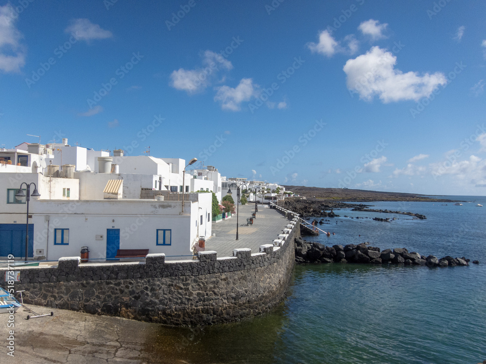 Vista panorámica de la arquitectura tradicional de pequeñas casa blancas con ventanas de madera de colores junto al mar cristalino en Lanzarote, c en el pueblo de Punta Mujeres en las Islas Canarias.