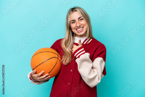 Young caucasian basketball player woman isolated on blue background giving a thumbs up gesture