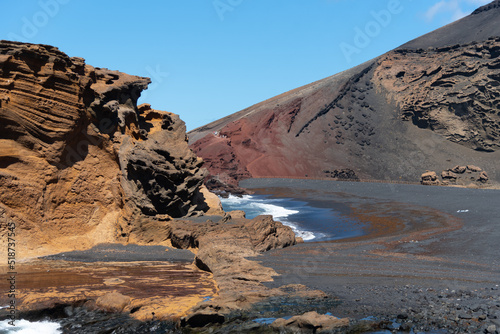 Vista panorámica de la Playa del Golfo en la isla de Lanzarote. Mar turquesa con olas rompiendo sobre la roca arena negra rodeada de montañas volcánicas y rocosas. Naturaleza de las Islas Canarias photo