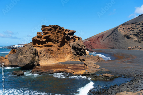 Vista panorámica de la Playa del Golfo en la isla de Lanzarote. Mar turquesa con olas rompiendo sobre la roca arena negra rodeada de montañas volcánicas y rocosas. Naturaleza de las Islas Canarias photo