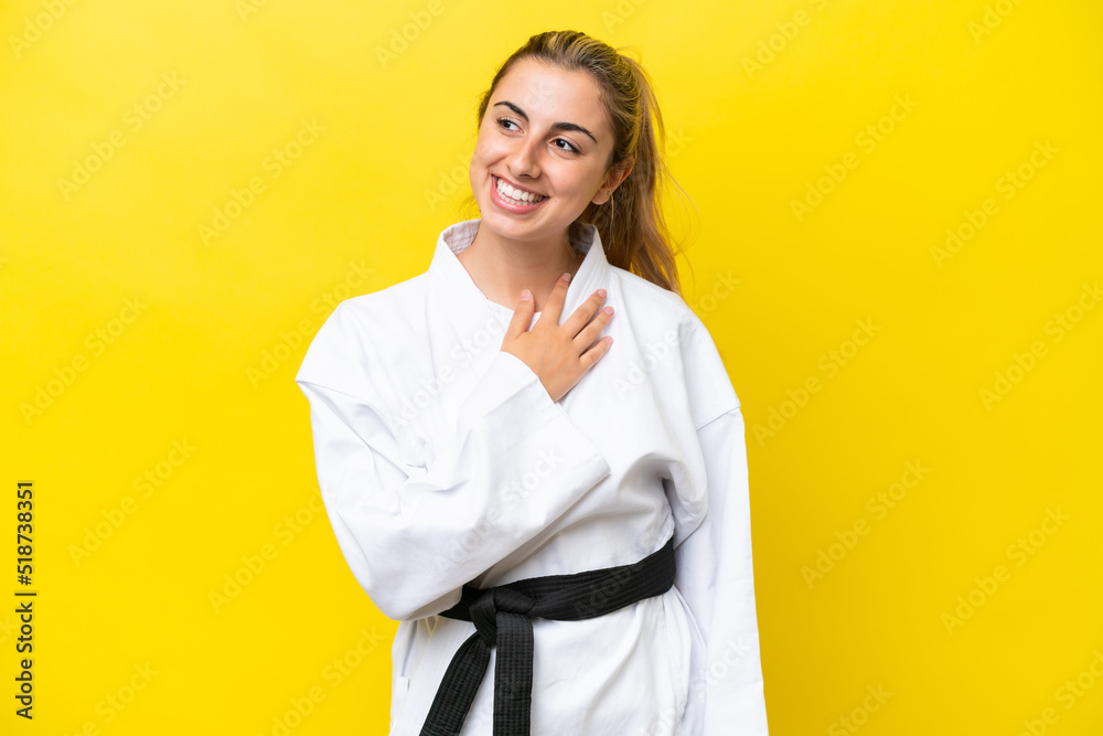 Young caucasian woman doing karate isolated on yellow background looking up while smiling Young caucasian woman doing karate isolated on yellow background looking up while smiling