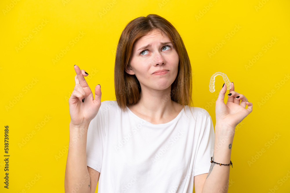 Young English woman holding invisible braces with fingers crossing and wishing the best Young English woman holding invisible braces with fingers crossing and wishing the best