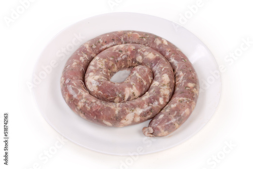 Coiled raw pork sausage on dish on a white background