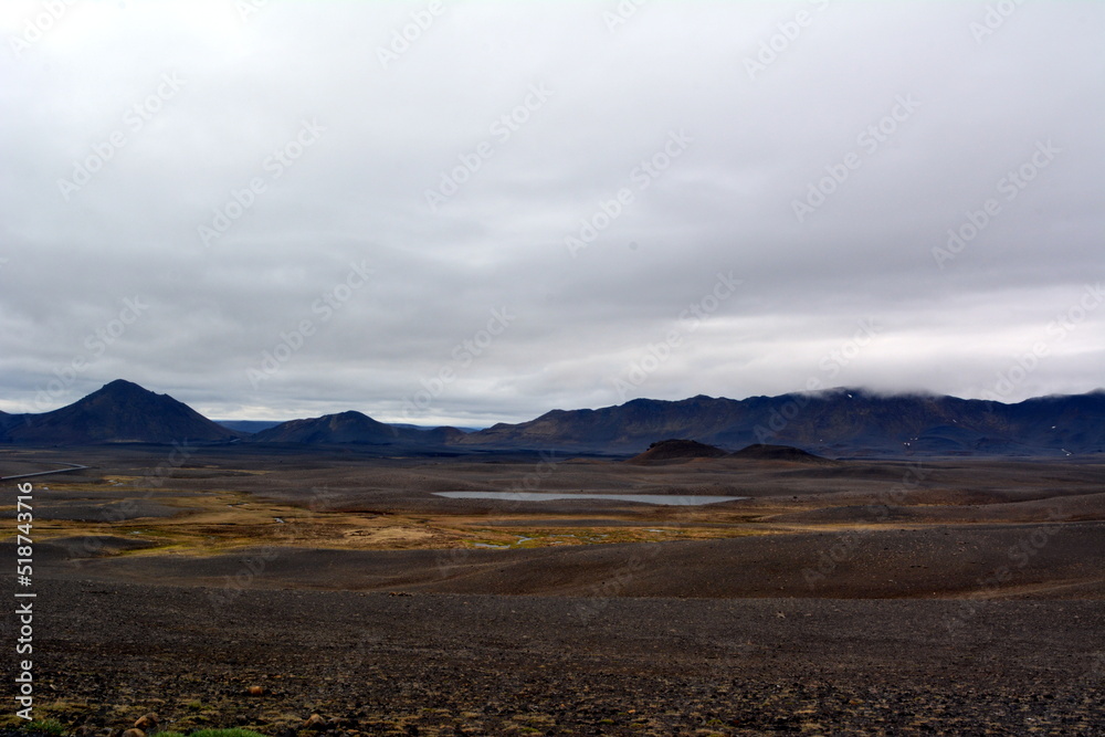 Lava field in Iceland Dettifoss Falls area on the background of distant mountains and stormy sky.