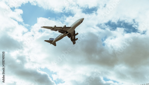 Passenger aircraft flying in the cloudy sky after take off. White clouds in the blue summer sky. Bussiness trip. Adventure and journey concept.