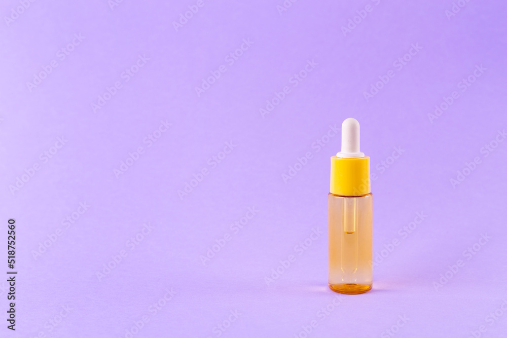 glass yellow bottle with pipette with essential oil on purple background top view. Aromatic cosmetic product for skin hair care Moisturizing beauty product with vitamin C close up glass yellow bottle with pipette with essential oil on purple background top view. Aromatic cosmetic product for skin hair care Moisturizing beauty product with vitamin C close up
