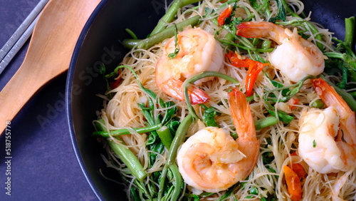 Stir fried rice noodle with shrimp and water minosa vegetable or Mee Phat Krachet Koong in Thai on black background. photo