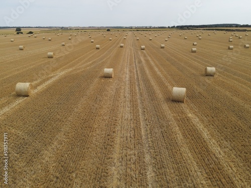 Drone high view of sunny day UK field with hay bales