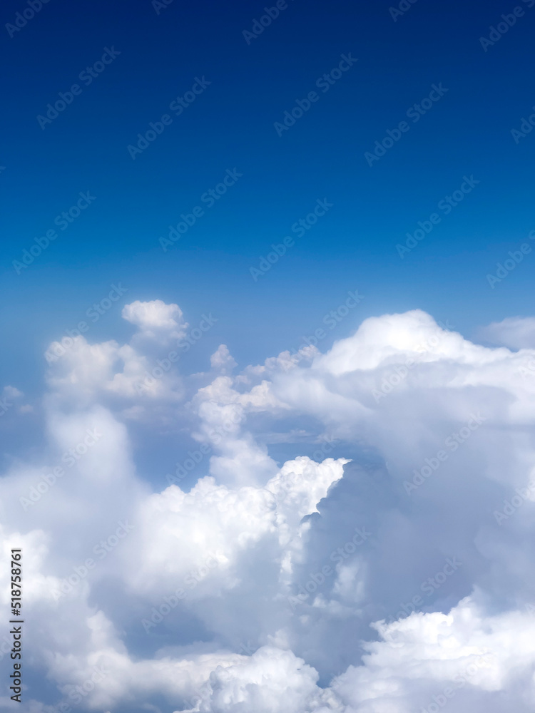 Naklejka premium High up fluffy clouds. Beautiful sky view from airplane window. Air travel background with copy space. Looking out aircraft bull's eye. Beautiful scenery from the air through plane porthole.