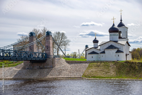 View of the chain bridge and the Church of St. Nicholas the Wonderworker, the city of Ostrov. Pskov region, Russia photo