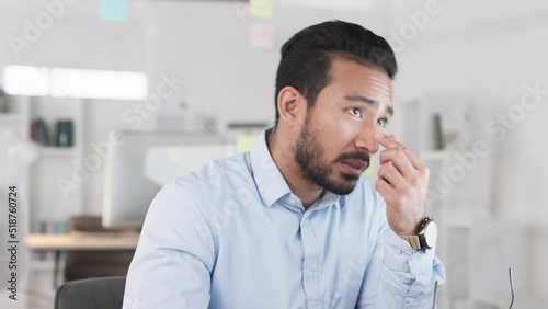 Stressed business man with a headache working on a computer in an office. Frustrated, tired and worried entrepreneur struggling to deal with burnout, eye strain and problems with difficult deadlines