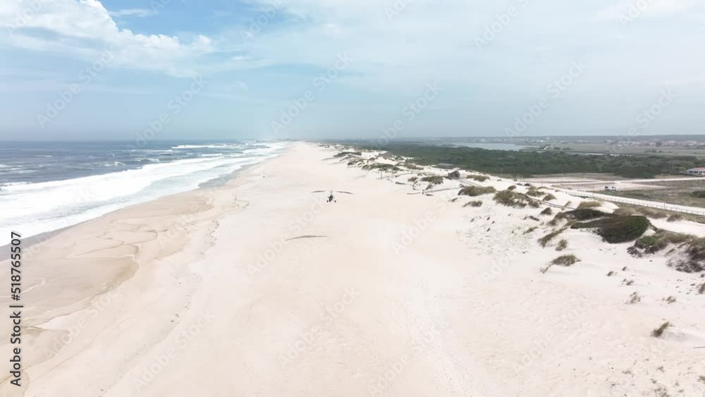 Huge totally empty beach with large area of dunes on the coast of Portugal. Paramotor flying over the beach. Huge totally empty beach with large area of dunes on the coast of Portugal. Paramotor flying over the beach.