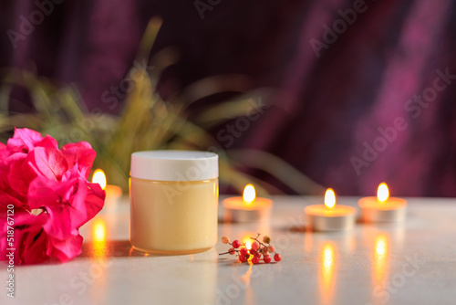 bottle of cream with flowers berries and candles photo