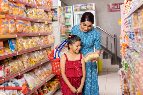 Photography Happy mother and daughter reading product information while shopping at supermar
