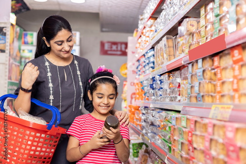 Photography Happy mother and daughter reading product information while shopping at supermar