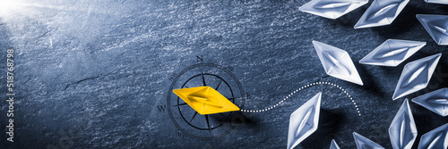 Yellow Paper Boat With Compass Leaving Group And Changing Direction - Entrepreneur/Business Opportunity photo