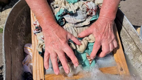 Female hands washing clothes on a washboard in village photo