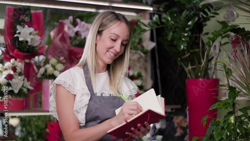 Beautiful Flower Shop Worker Checking Flowers And Holding Clipboard