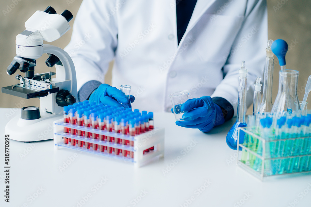 A professional male scientist in glasses and a protective mask conducts experiments with reagents in a laboratory. stop the spread of corona virus medical concept A professional male scientist in glasses and a protective mask conducts experiments with reagents in a laboratory. stop the spread of corona virus medical concept