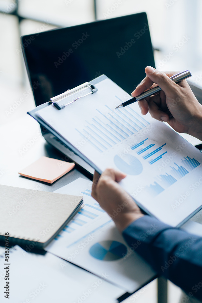 The hands of a male businessman are analyzing and calculating the annual income and expenses in a financial graph that shows results To summarize balances overall in office