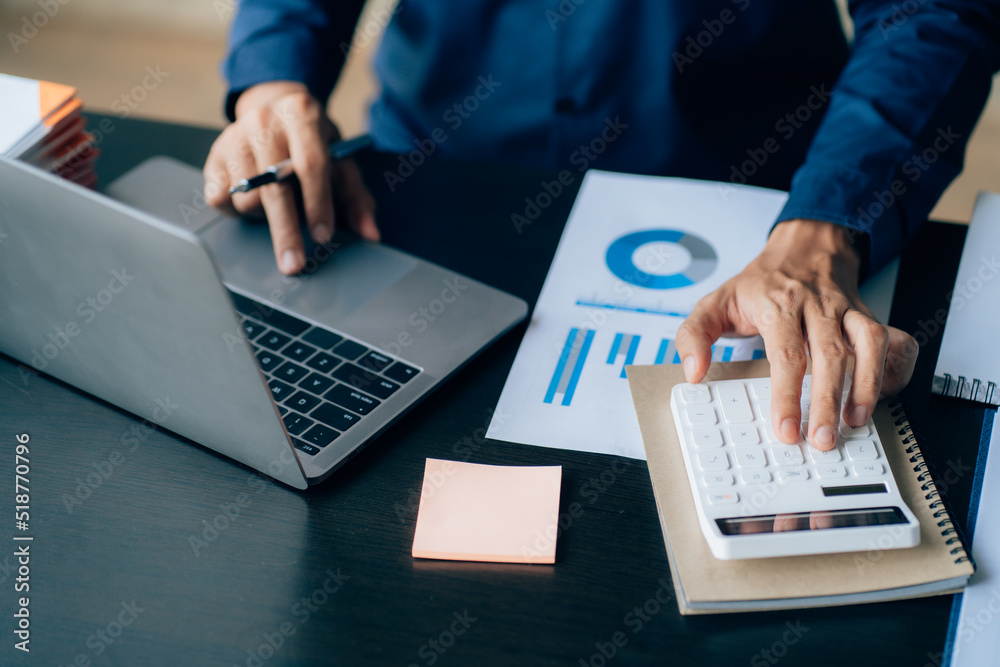 The hands of a male businessman are analyzing and calculating the annual income and expenses in a financial graph that shows results To summarize balances overall in office