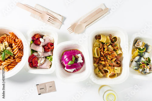 Collection of white plastic take away boxes with healthy food. Set of containers with everyday meals - meat, vegetables and law fat snacks on white background. wooden cutlery