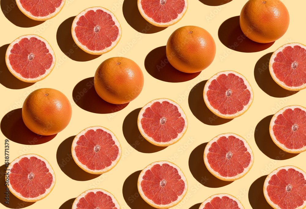 Grapefruit pattern on a beige background. Orange juicy grapefruit cut with shadow. Fruit food concept. Grapefruit pattern on a beige background. Orange juicy grapefruit cut with shadow. Fruit food concept.