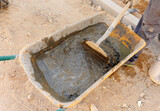 Albañil mezclando agua, arena y cemento para hacer mortero de hormigón en una carretilla de obra a la manera tradicional 