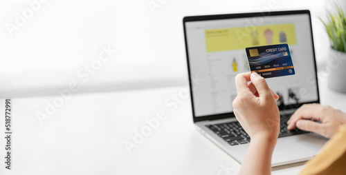 Woman holding credit card shopping online with laptop computer.