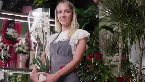 Portrait Of A Beautiful Girl At Her Flower Shop Holding A Plant, Flower. Small business, florst, entrepreneurship concept. 