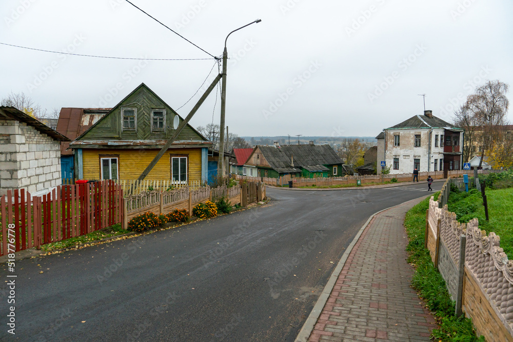 Low small wooden houses along a narrow cozy street. The historical center of a small Belarusian town.