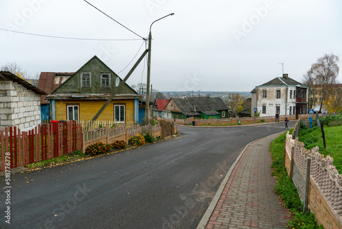 Fototapeta Naklejka Na Ścianę i Meble -  Low small wooden houses along a narrow cozy street. The historical center of a small Belarusian town.