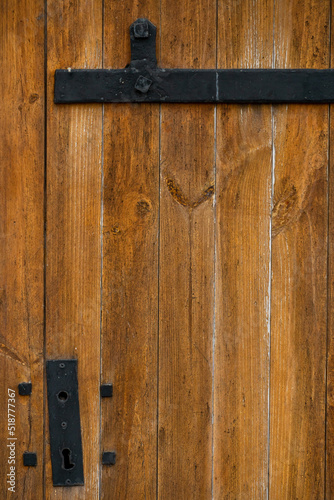 Beautiful old wooden door in the church. Wooden orange background. Rusty hinges and awnings on antique gates. © Pokoman