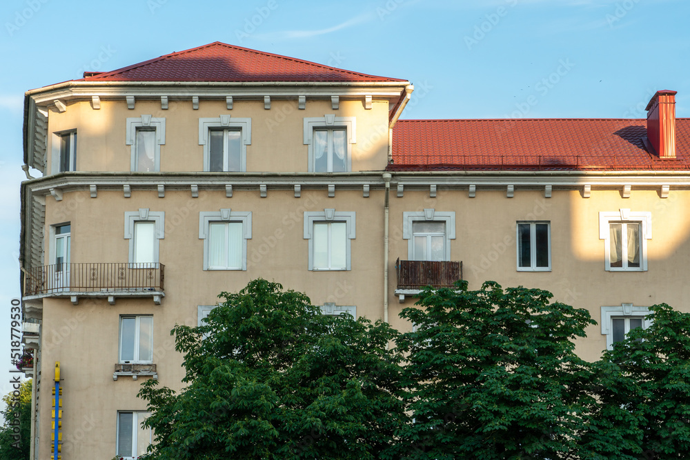 Panel residential building surrounded by greenery and trees. A green city in an ecologically clean area. The house is flooded with the orange light of the setting sun