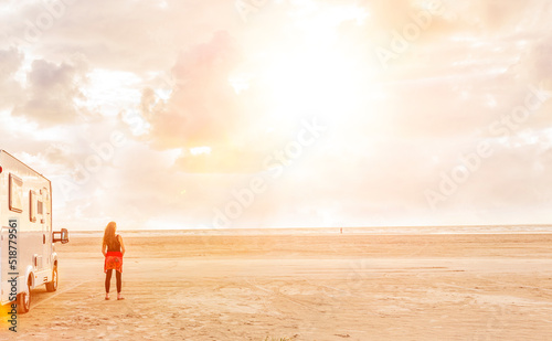 Frau neben einem Camper an einem Meeresstrand