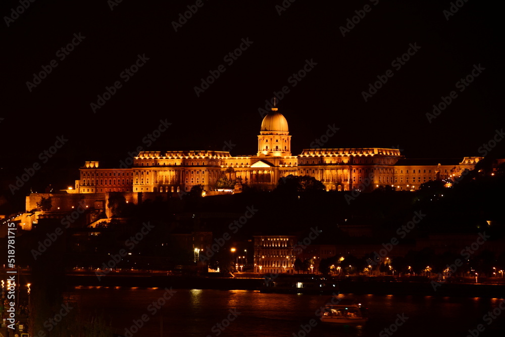 panoramic night view of the royal castle building complex in Budapest, Hungary. brightly lit palace with large stone cupola along the Danube. travel and tourism concept. European architecture. 